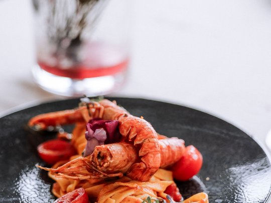 Family hotel vicino a Vipiteno: “hallo” e benvenuti! Piatto di pasta con gamberi e pomodorini su piatto nero