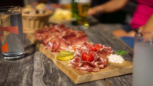 Ski touring in Pflerschtal Wooden board with cold cuts, pickles, tomatoes and cheese on outdoor rustic table