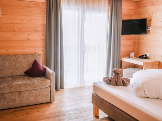 Hotel im Pflerschtal: Aktivhotel Panorama Gemütliches Hotelzimmer mit Sofa, Bett und Handtuchkunst auf Bett