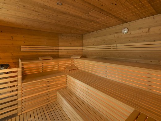 Skifahren in Ladurns Innenansicht einer traditionellen Sauna aus Holz mit mehrstufigen Bänken und Ofen