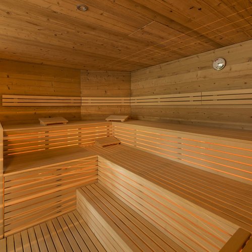 Wellness in der Unterkunft im Pflerschtal Innenansicht einer traditionellen Sauna aus Holz mit mehrstufigen Bänken und Ofen