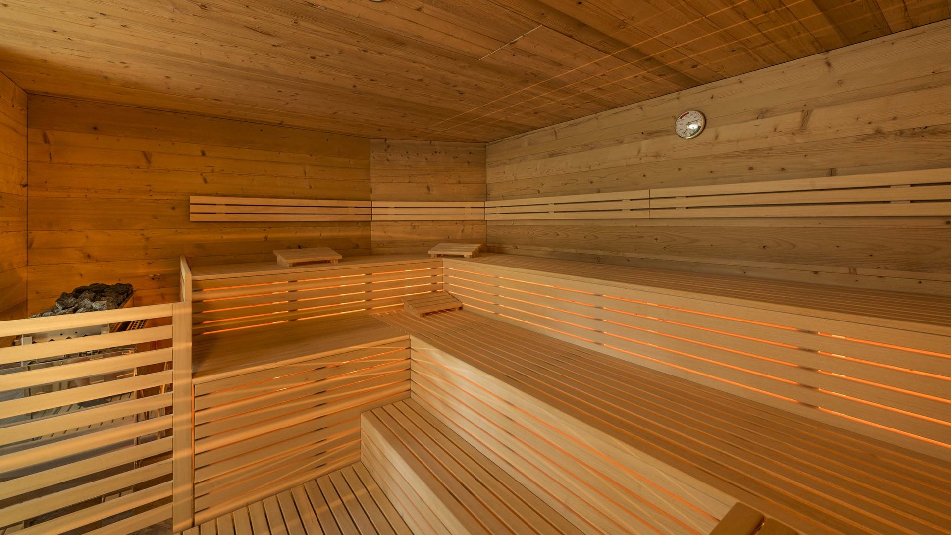 Wellness in der Unterkunft im Pflerschtal Innenansicht einer traditionellen Sauna aus Holz mit mehrstufigen Bänken und Ofen