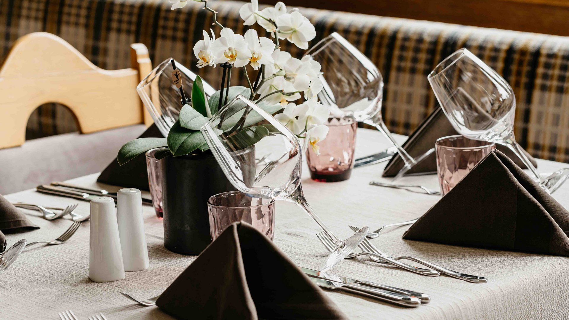 Family hotel vicino a Vipiteno: “hallo” e benvenuti! Tavolo elegante apparecchiato con orchidee bianche e bicchieri da vino