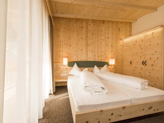 Hotel in Pflerschtal: rooms and offers Cozy bedroom with wooden furniture and bed in natural daylight