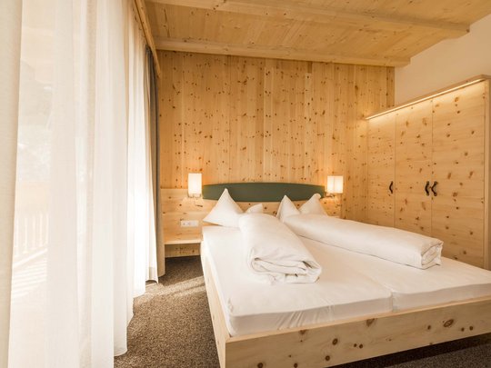 Hotel in Pflerschtal: Aktivhotel Panorama Cozy bedroom with wooden furniture and bed in natural daylight