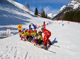 Skifahren in Ladurns Skilehrer mit Kindern in gelben Westen beim Skiunterricht im Schnee