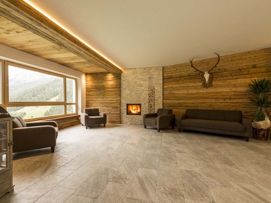 Hotel in Pflerschtal: Aktivhotel Panorama Cozy living room with fireplace, brown armchairs, sofa, and large window with mountain view