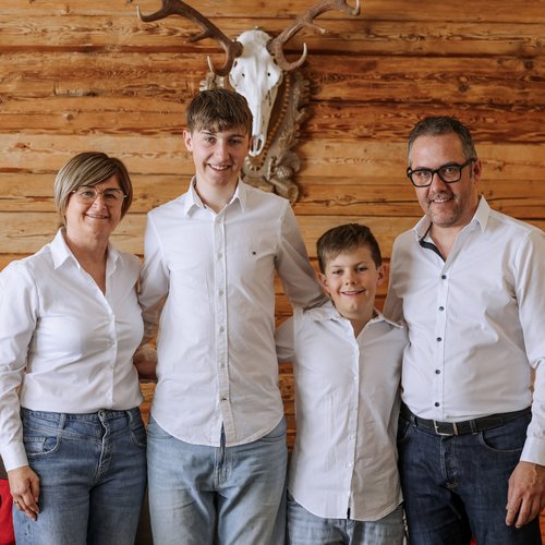 Family hotel in South Tyrol: Hotel Panorama Family in white shirts standing before wall with deer antlers