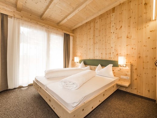 Hotel in Pflerschtal: Aktivhotel Panorama Cozy bedroom with wooden walls and double bed illuminated by natural daylight