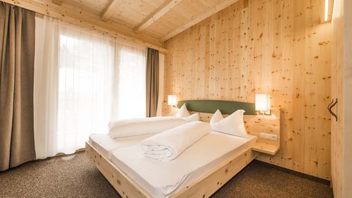 Ski touring in Pflerschtal Cozy bedroom with wooden walls and double bed illuminated by natural daylight