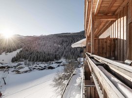 Familienhotel in Südtirol: Hotel Panorama Balkon eines Holzchalet mit Blick auf verschneite Berge und Sonnenaufgang