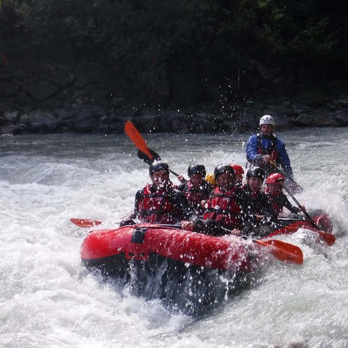 Aktivhotel in Südtirol: Sommererlebnisse Gruppe paddelt in einem roten Schlauchboot auf Wildwasserfluss