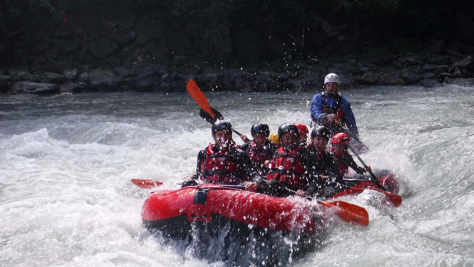 Hotel mit Bergpanorama und GossensassCARD Gruppe paddelt in einem roten Schlauchboot auf Wildwasserfluss