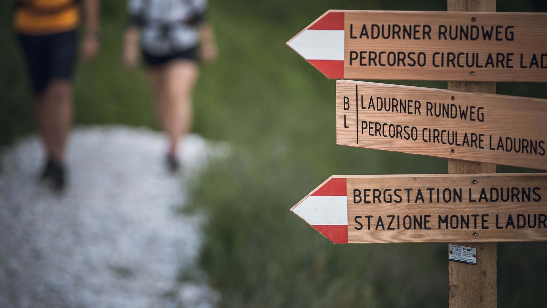 Aktivhotel Panorama: hiking Signpost for Ladurner circular trail and mountain station with hikers in the background