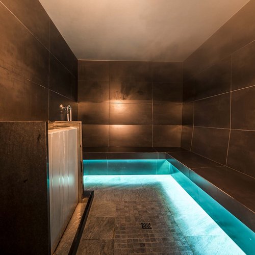 Wellness in der Unterkunft im Pflerschtal Moderner Dampfraum mit dunklen Fliesen und blauem Beleuchtungsakzent