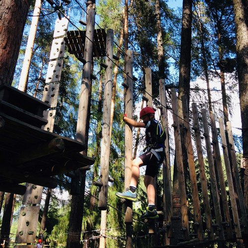 I nostri alloggi a Colle Isarco: una base per mille avventure Bambino arrampicato in un parco avventura tra gli alberi con attrezzatura di sicurezza