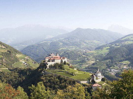 Hotel Panorama in Gossensass – Unterkunft zum Träumen Burg auf einem bewaldeten Hügel mit Berglandschaft im Hintergrund