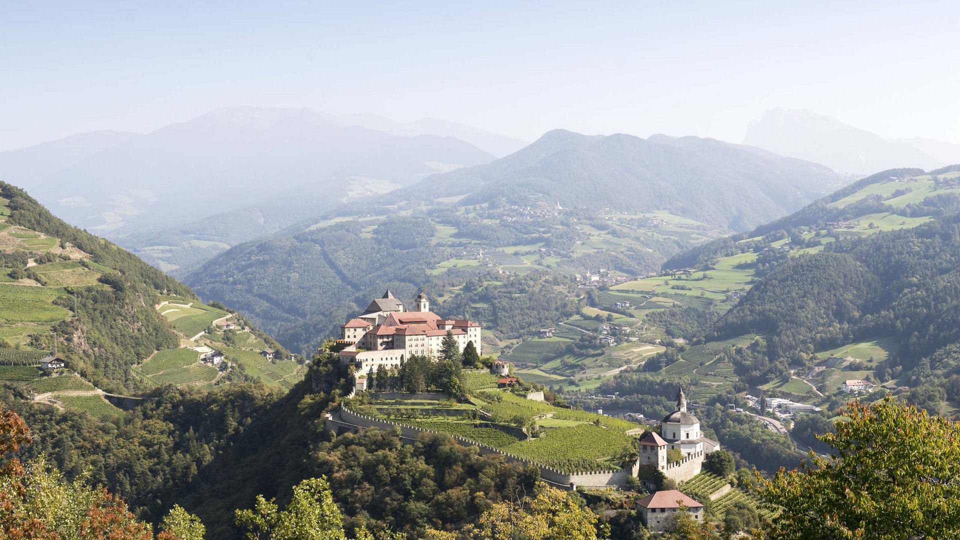 Hotel Panorama in Gossensass – Unterkunft zum Träumen Burg auf einem bewaldeten Hügel mit Berglandschaft im Hintergrund