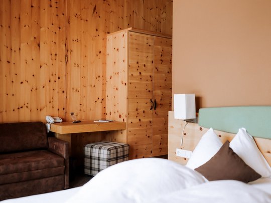 Family hotel vicino a Vipiteno: “hallo” e benvenuti! Camera d'hotel con pareti in legno, letto, divano e armadio