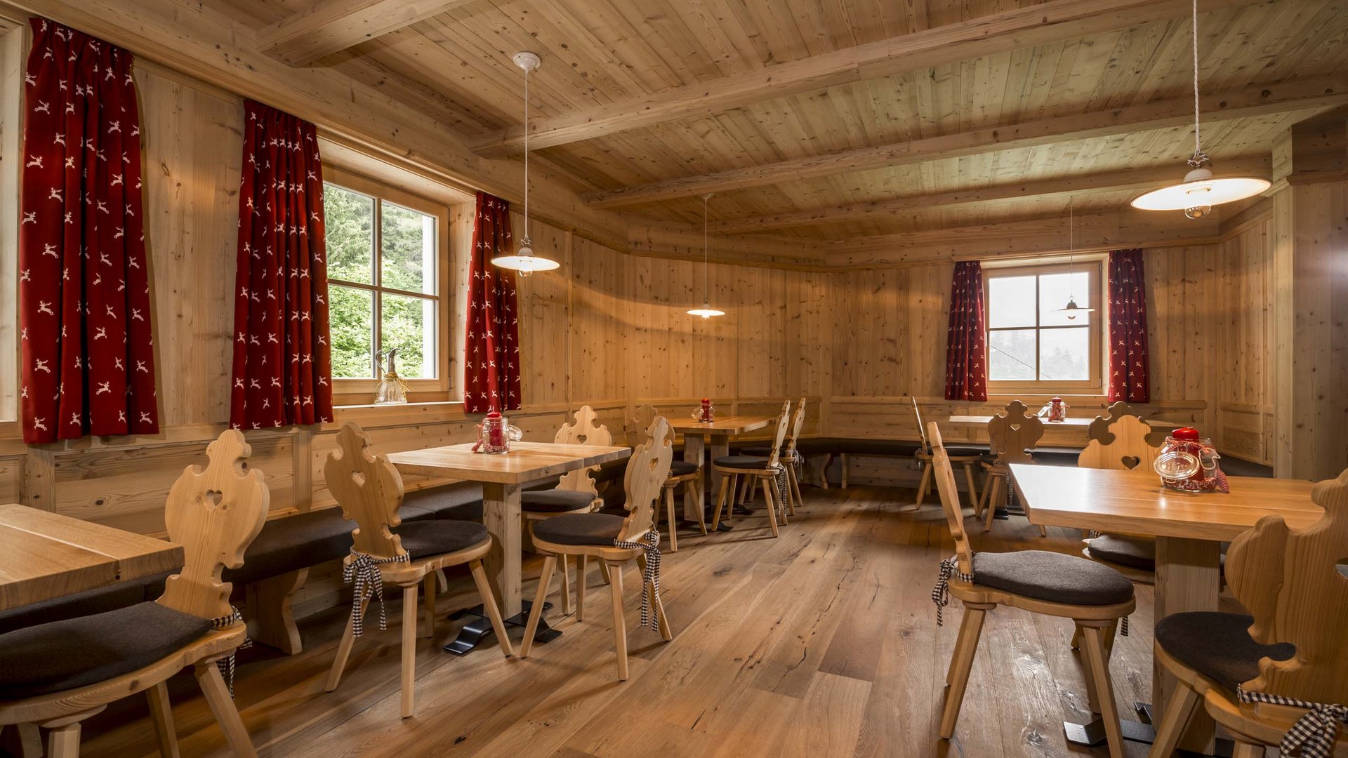 Genuss aus Pflersch: Hotel Panorama Rustikaler Speiseraum mit Holzvertäfelung und roten Vorhängen