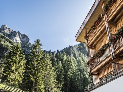 Hotel in Pflerschtal: Aktivhotel Panorama Wooden house with flowers by forested mountains under clear sky