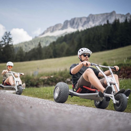 I nostri alloggi a Colle Isarco: una base per mille avventure Due persone guidano tricicli a pedali su una strada di montagna
