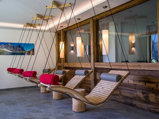 Familienhotel in Sterzing: hoi und herzlich willkommen! Hängende Holzliegen mit Kopfstützen und bunten Decken in modernem Wellnessraum
