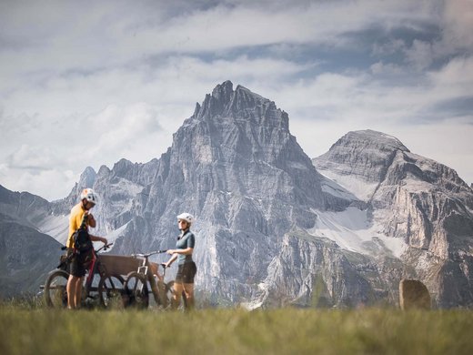 Il Panorama: il vostro family hotel e i suoi servizi inclusi Due ciclisti con caschi davanti a montagne rocciose alte sotto un cielo nuvoloso