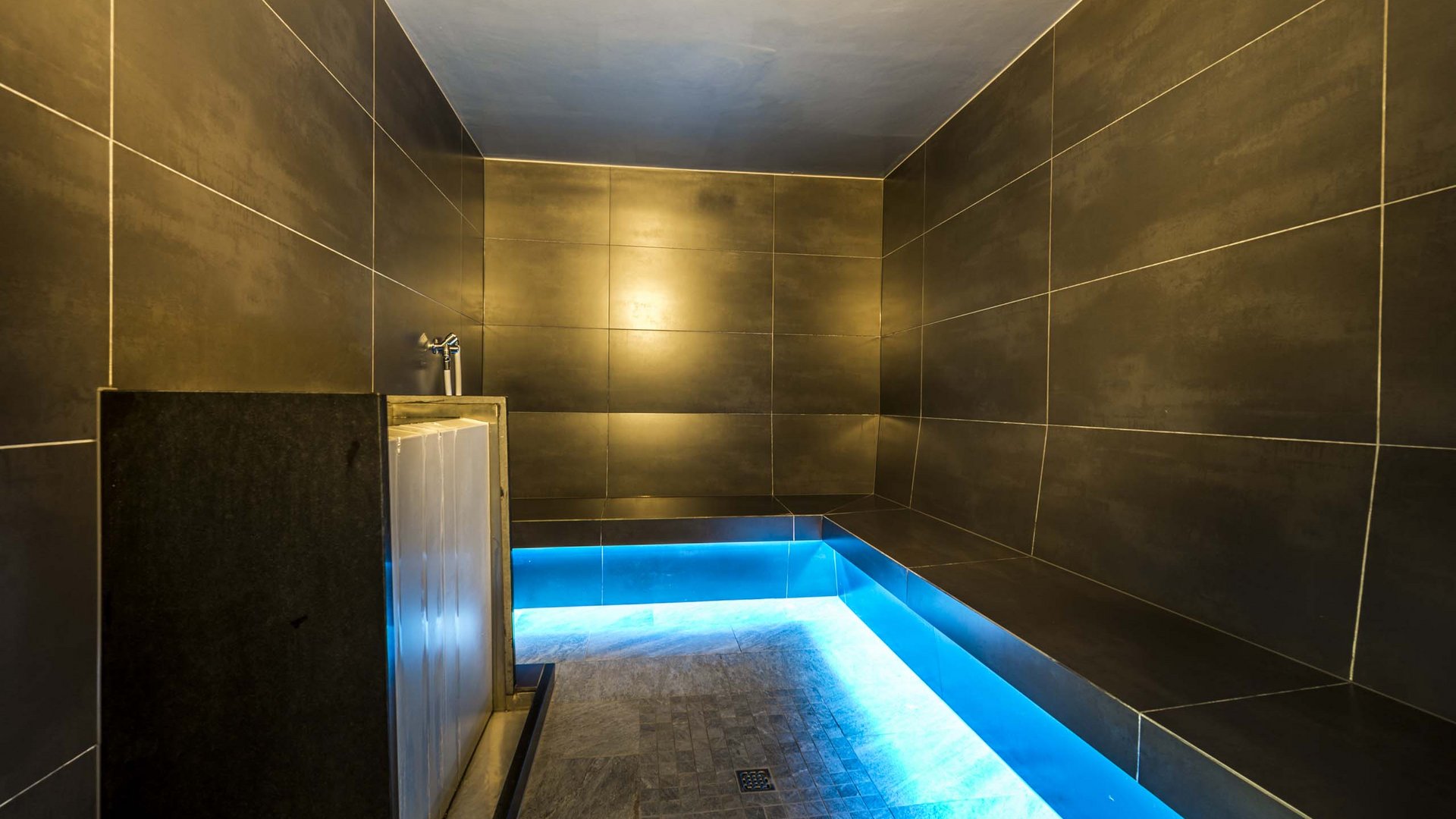 Wellness in der Unterkunft im Pflerschtal Moderner Dampfbadraum mit schwarzer Fliesenwand und blauer LED-Beleuchtung