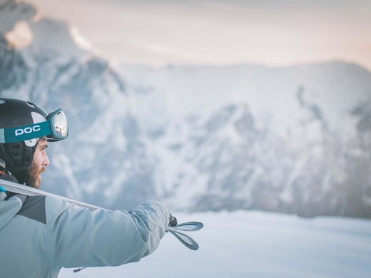 Familienhotel in Sterzing: hoi und herzlich willkommen! Skifahrer mit Helm und Skiern blickt auf schneebedeckte Berge