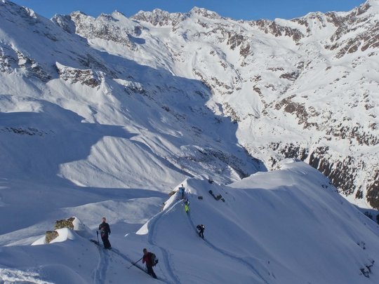Ski touring in Pflerschtal Skiers climbing snow-covered mountain with alpine landscape in the background