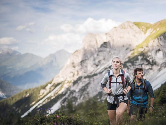 Aktivhotel Panorama: Wandern Zwei Wanderer mit Rucksäcken in den Bergen bei sonnigem Wetter