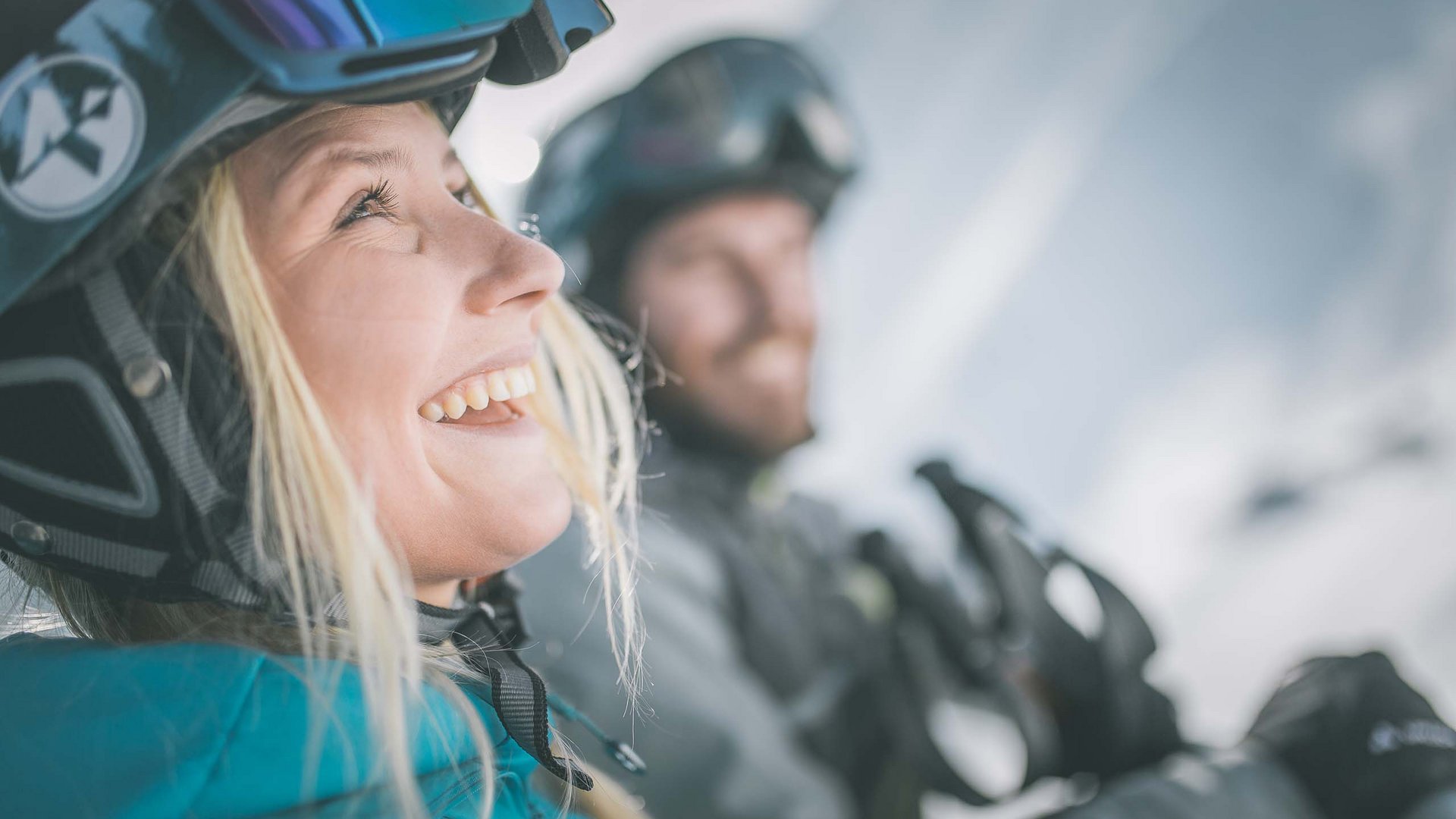 Skifahren in Ladurns Lachende Frau und Mann mit Skiausrüstung und Helmen in verschneiter Berglandschaft