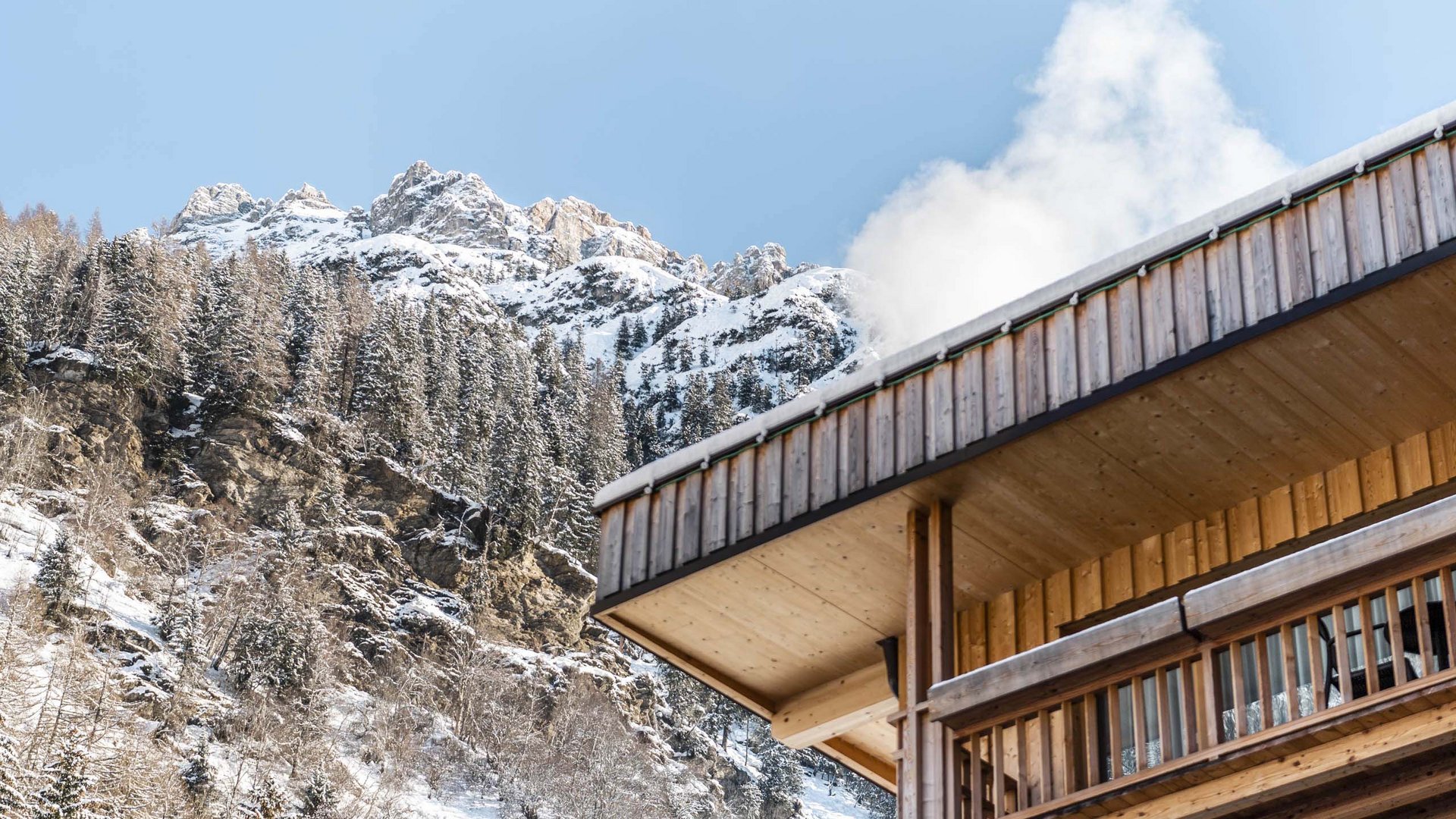 Un family hotel in Val di Fleres: l’Hotel Panorama Casa di legno con fumo e montagne innevate sullo sfondo