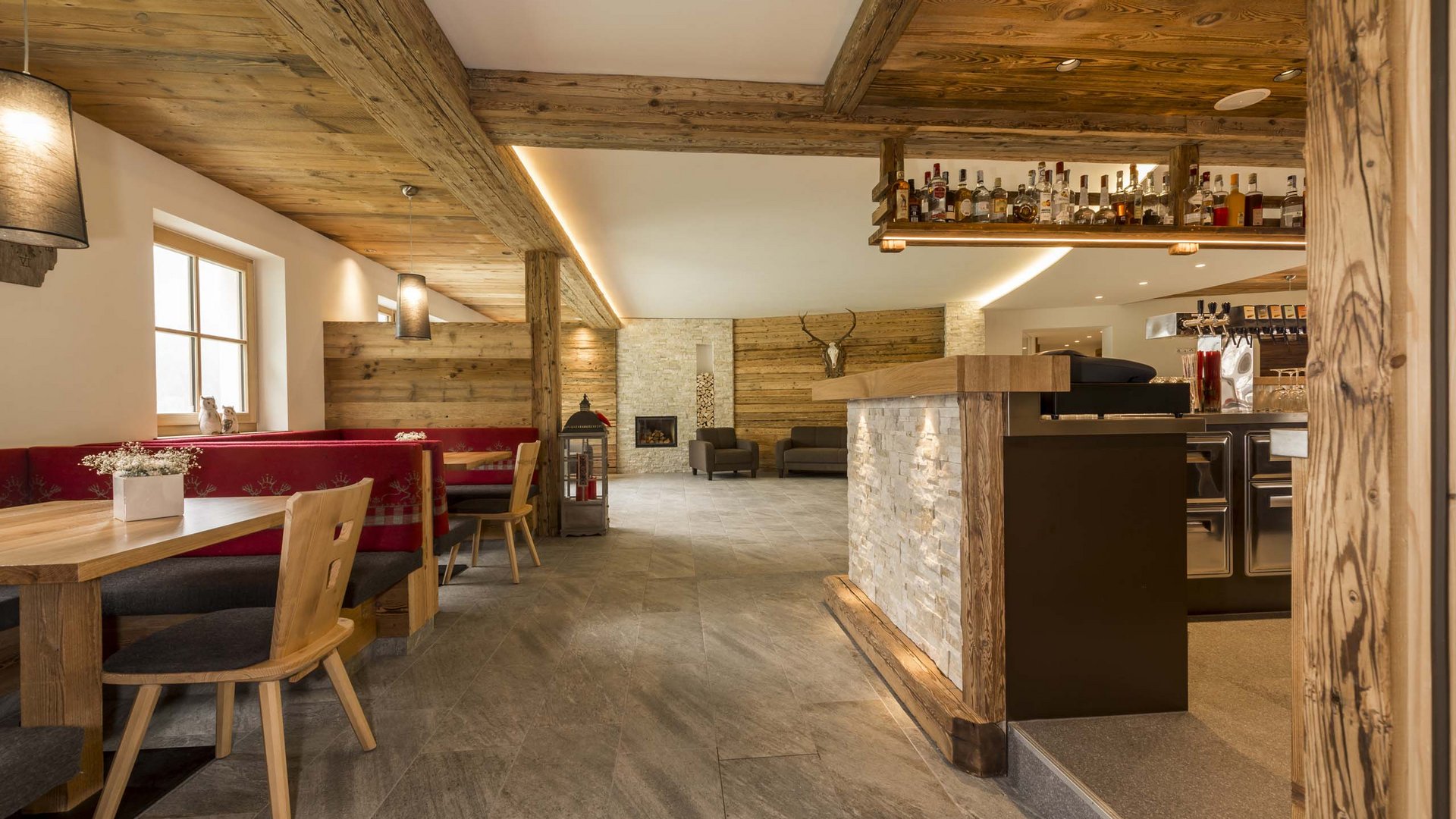 Hotel in Pflerschtal: Aktivhotel Panorama Cozy bar with wooden furniture, red benches, and fireplace