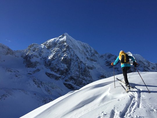 Ski touring in Pflerschtal Skier ascending snowy mountain under clear blue sky