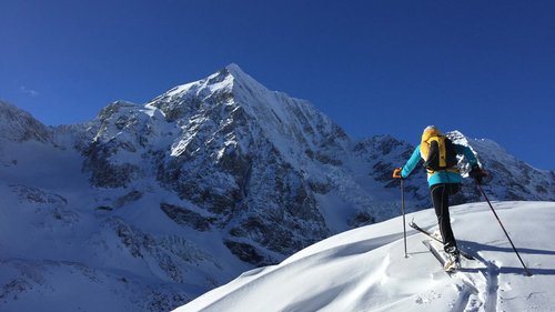 Ski touring in Pflerschtal Skier ascending snowy mountain under clear blue sky