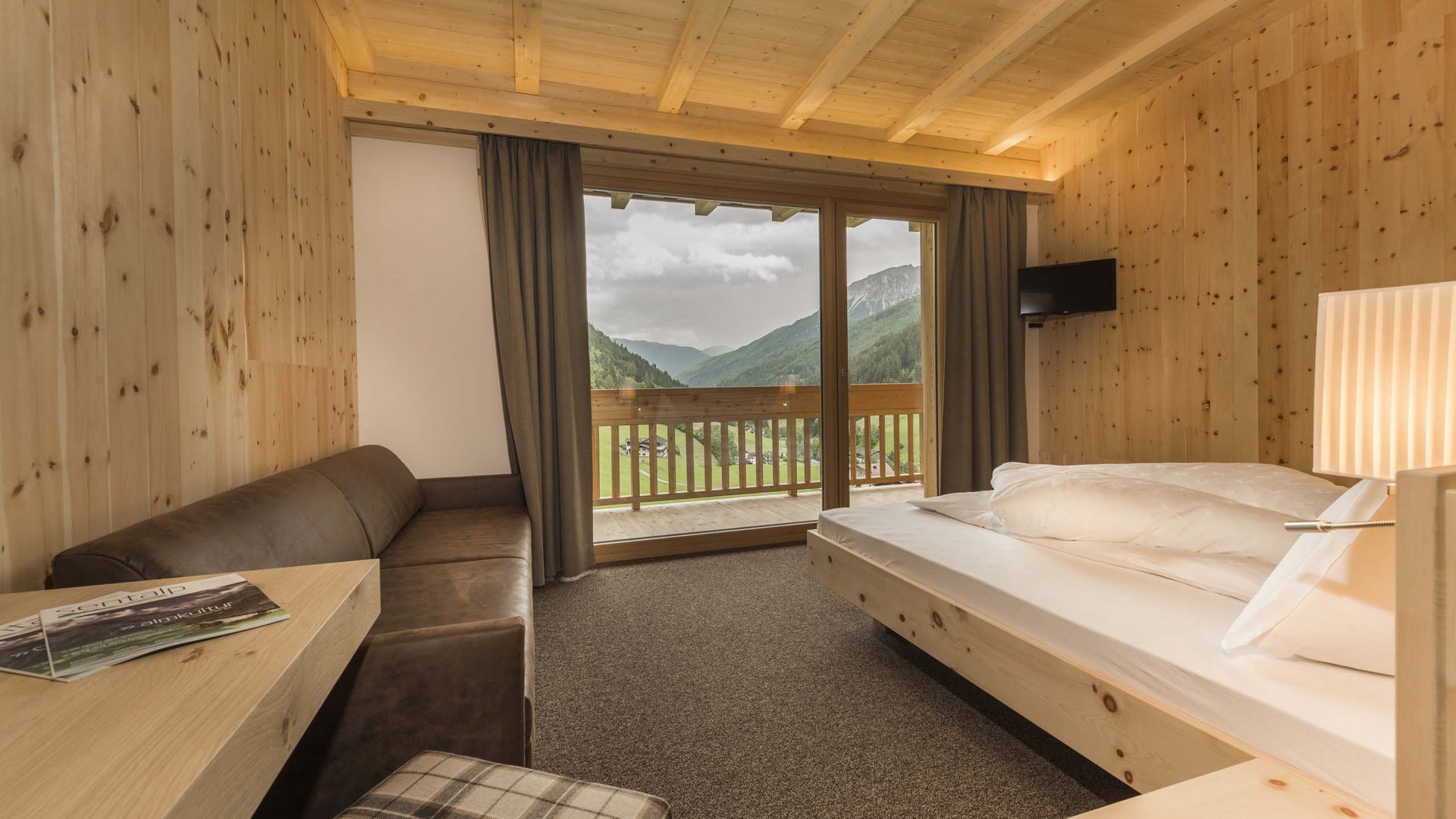 Un hotel a Colle Isarco? Ecco le nostre camere e offerte Camera accogliente in legno con balcone e vista sulle montagne