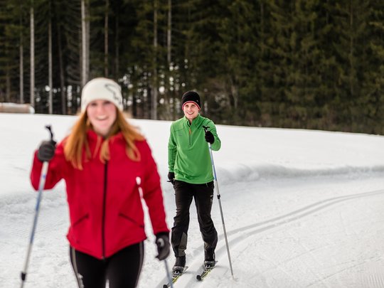 Pflerschtal: Skigebiet, Wandergebiet und mehr Zwei Personen beim Langlaufen auf verschneiter Strecke vor Wald