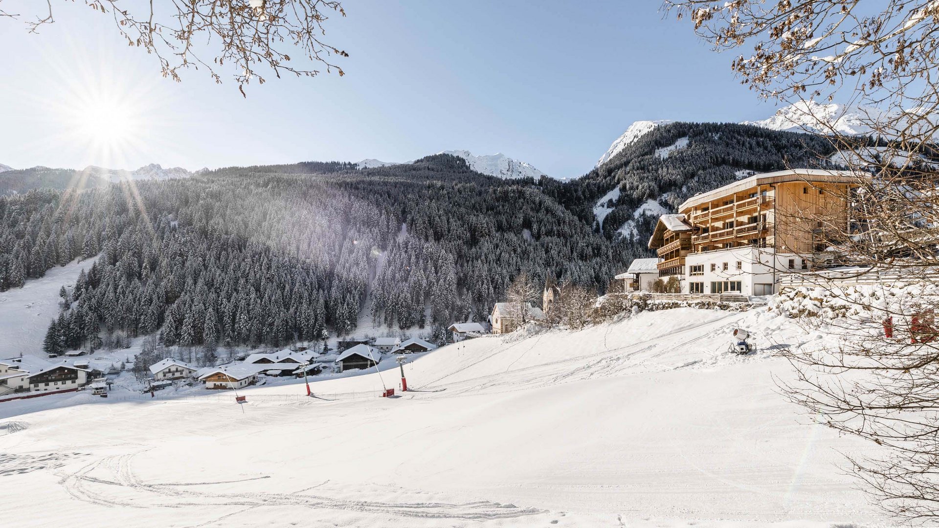 Un family hotel in Val di Fleres: l’Hotel Panorama Paesaggio montano innevato con sole e case sulla collina