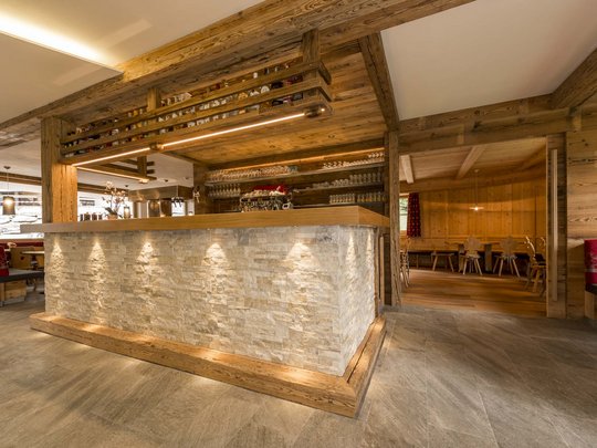 Hotel in Pflerschtal: Aktivhotel Panorama Rustic wooden bar with stone facade and lit shelves inside a restaurant